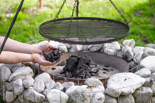 Grill ogrodowy z wiszącym okrąglym rusztem nad paleniskiem rozpalany węglem drzewnym 