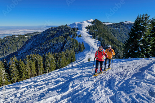 Man and woman hiking with snowshoes at Hoerlne, Ammergau Alps, Upper Bavaria, Bavaria, Germany photo