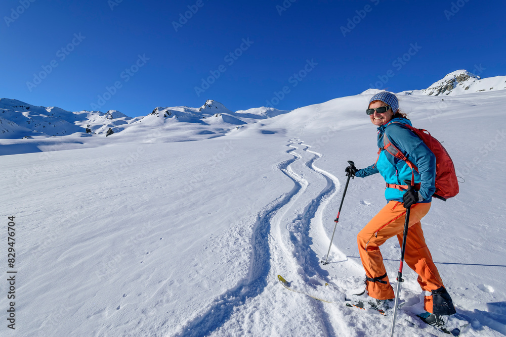 Happy mature woman back country skiing with ski poles at Schwebenkopf, Kurzer Grund, Kitzbuehel Alps, Tyrol, Austria Happy mature woman back country skiing with ski poles at Schwebenkopf, Kurzer Grund, Kitzbuehel Alps, Tyrol, Austria
