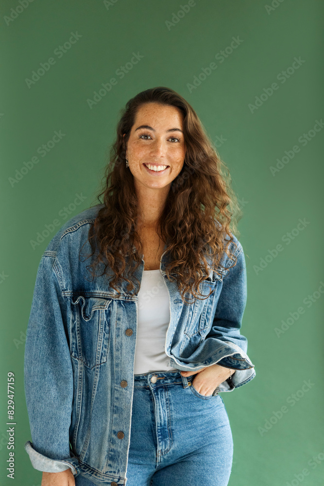 Smiling woman with hand in pocket standing against green background Smiling woman with hand in pocket standing against green background