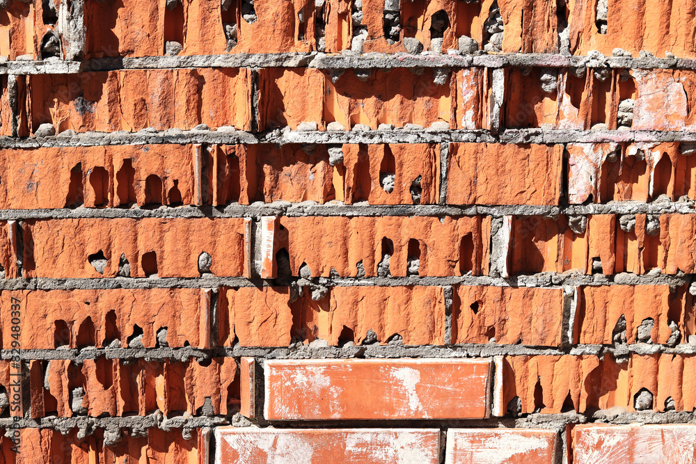Clinker brick, a type of ceramic brick. Destruction of the wall. Old brick wall with broken orange bricks. Texture