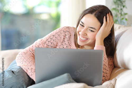 Happy woman on a sofa watching media on laptop photo