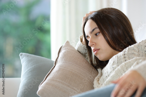 Worried woman on a couch looking away