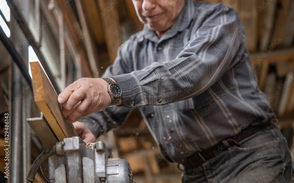 Senior man processing wooden plank on machine in workshop Senior man processing wooden plank on machine in workshop