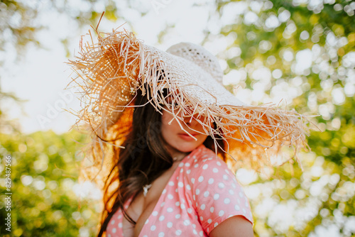 Woman obscuring face with straw hat photo