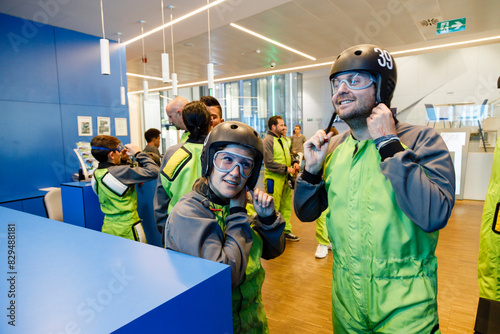 Smiling man and woman fastening helmet at indoor skydiving center photo
