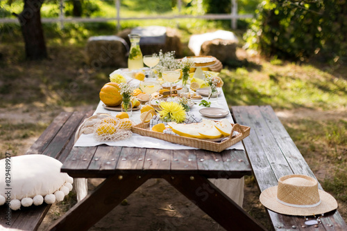 Wooden picnic table decorated with various food in garden