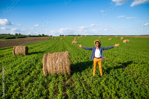 African farmer is standing in his agricultural field. He is cultivating clover and making bales of hay. photo