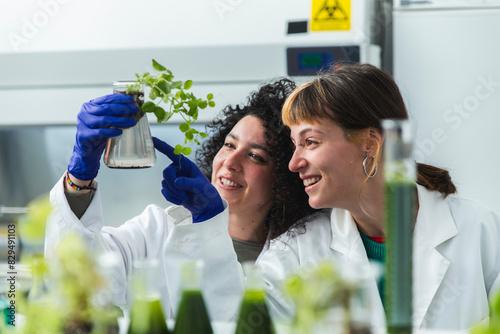 Smiling scientists examining samples of pea plants in laboratory