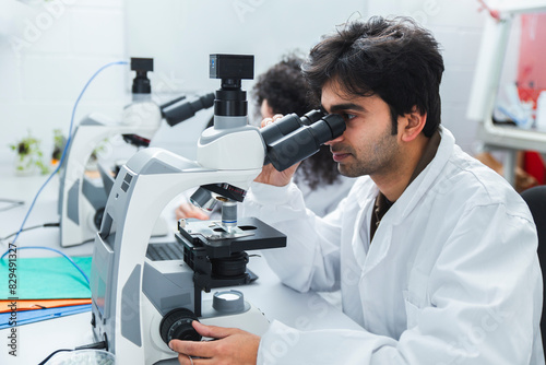 Scientist analyzing sample with microscope in laboratory photo