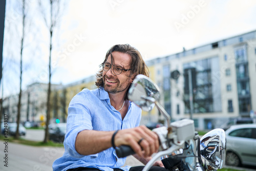 Smiling mature man riding motor scooter in city photo