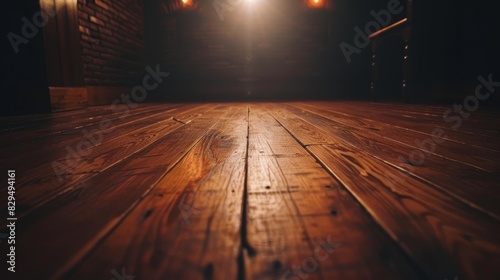  A dark room features a wooden floor illuminated by light, composed of interconnected planks