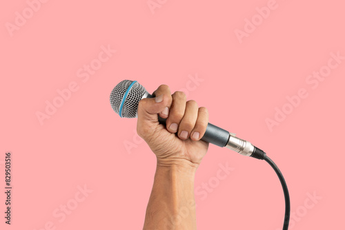 Black male hand holding a microphone isolated on pink background