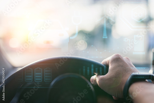 Close-up of a hand on a steering wheel with futuristic HUD display showcasing electric vehicle technology and battery levels.