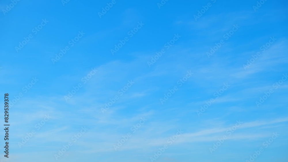 A clear blue sky with faint, wispy clouds dispersed throughout. The sky's gradient transitions from a deeper blue at the top to a lighter blue near the horizon, creating a calm and tranquil scene.

