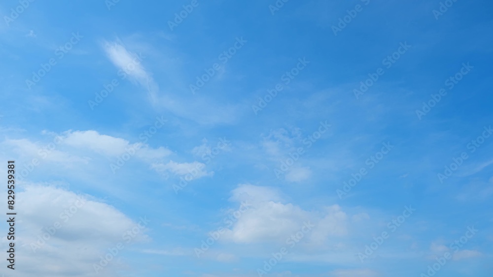 A serene blue sky with a few scattered white clouds. The clouds are thin and wispy, giving the sky a light and airy appearance. The blue hues range from light to medium. Cloud background.
