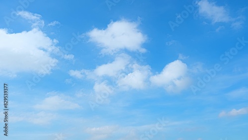 A bright blue sky scattered with fluffy white clouds. The clouds vary in size and shape  creating a dynamic and cheerful atmosphere against the clear blue backdrop. Blue sky background. 