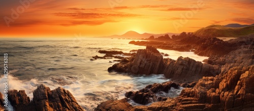 Rocky shoreline bathed in the warm glow of sunset providing a scenic view with copy space image