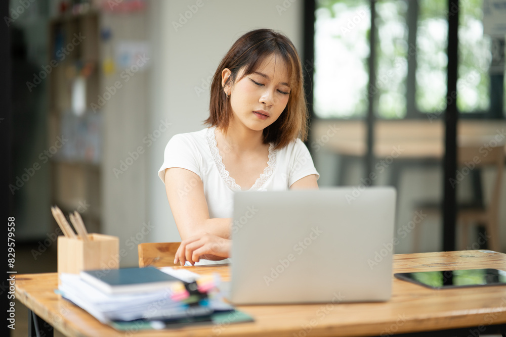 Asian business woman working on computer looking at documents at office Asian business woman working on computer looking at documents at office