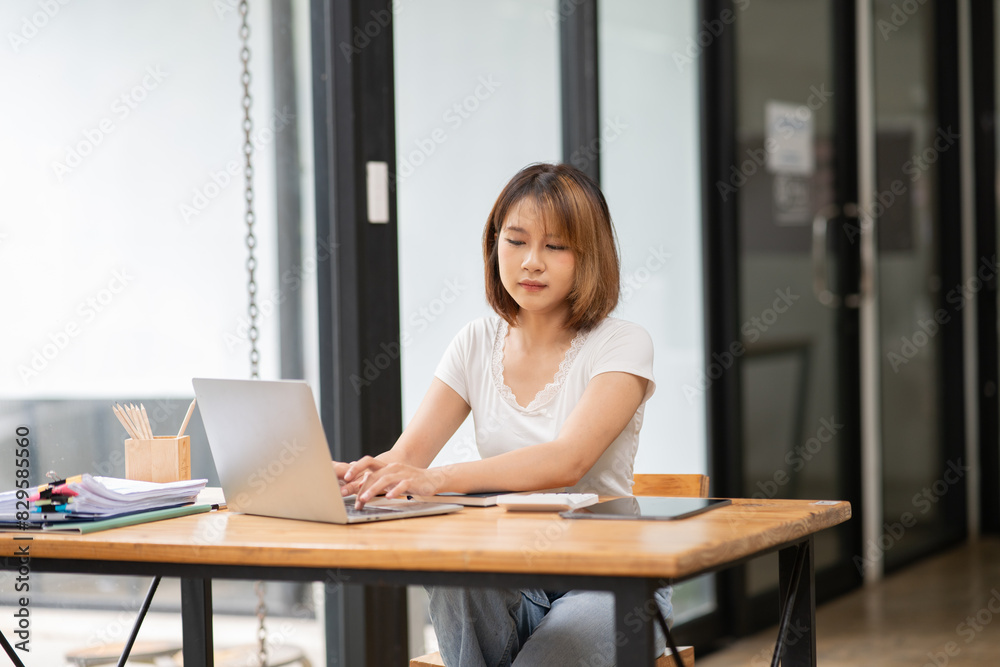 Asian business woman working on computer looking at documents at office Asian business woman working on computer looking at documents at office
