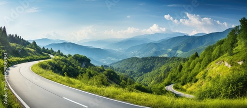 Scenic country road winding through lush green mountains in summer with copy space image