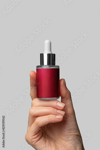 Woman's hand showing cosmetic product mockup of anti-aging serum with retinol. Cosmetic product branding mockup. Daily skincare and body care routine
