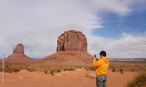 Young man taking photos of Merrick Butte using a smartphone. Monument Valley. Arizona. USA.