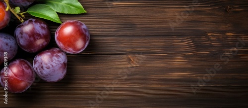 Top view of ripe juicy plums on a wooden surface with copy space image