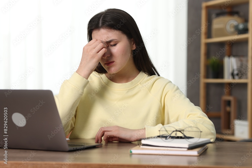 Overwhelmed woman sitting with laptop at table indoors Overwhelmed woman sitting with laptop at table indoors