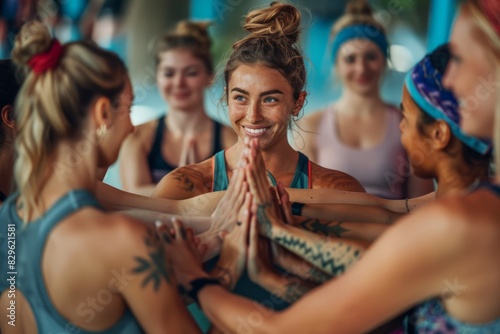 Group of diverse fitness friends putting their hands together in a huddle before a yoga session. People supporting each other in a community wellness centre. photo