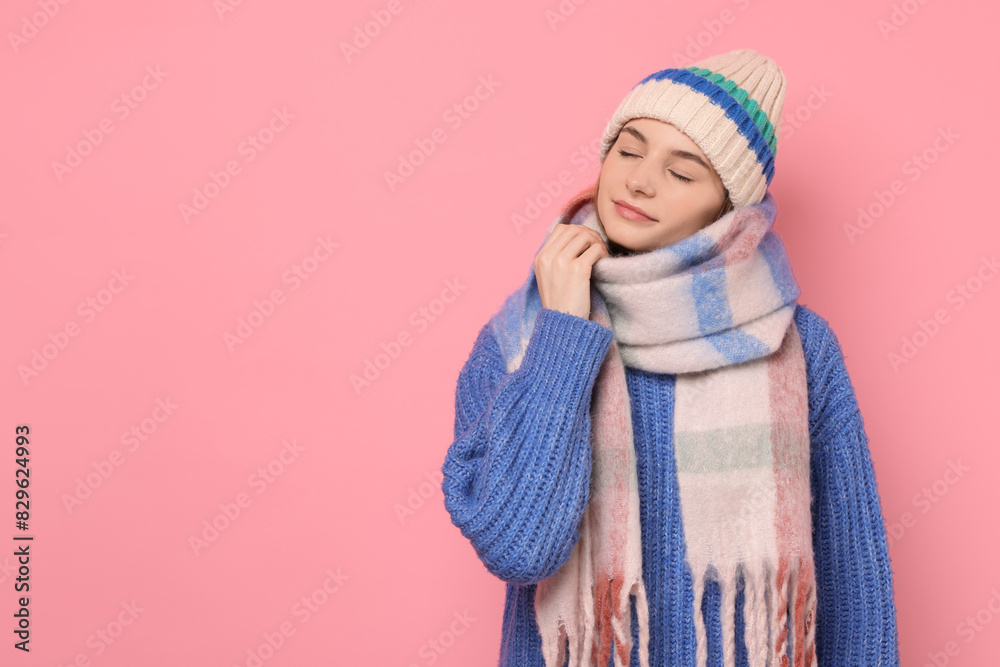Beautiful woman in warm scarf and hat on pink background, space for text