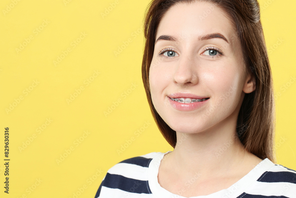 Portrait of smiling woman with dental braces on yellow background. Space for text Portrait of smiling woman with dental braces on yellow background. Space for text