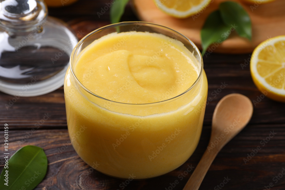 Delicious lemon curd in glass jar, fresh citrus fruit and spoon on wooden table, closeup Delicious lemon curd in glass jar, fresh citrus fruit and spoon on wooden table, closeup