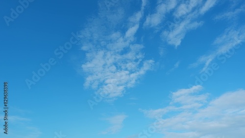 A clear blue sky with scattered white clouds. The clouds are thin and wispy  creating a delicate pattern against the bright blue background  conveying a peaceful and serene ambiance. 