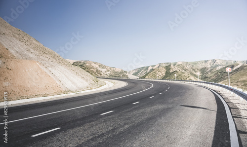 Asphalt road among mountains and hills in the mountains of Tajikistan, a beautiful road in nature, panoramic landscape on a summer day