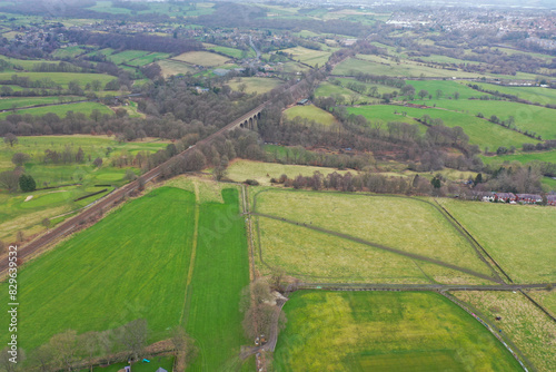 Aerial drone photo across the village of Lightcliffe in Halifax in West Yorkshire in the UK, showing the fields along side a train track viaduct, taken on a cold day in the winter time.