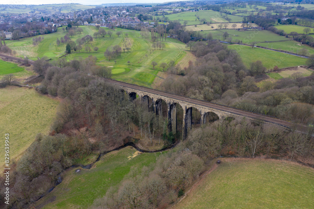 Aerial drone photo across the village of Lightcliffe in Halifax in West Yorkshire in the UK, showing the fields along side a train track viaduct, taken on a cold day in the winter time.