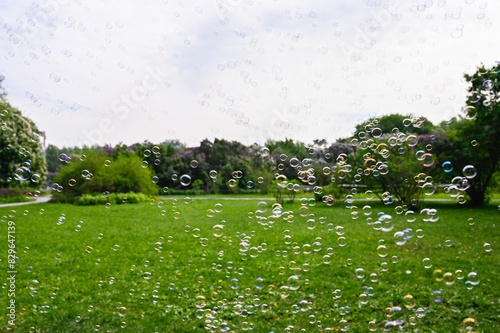 There are a lot of soap bubbles in the foreground and a park stands in the background.