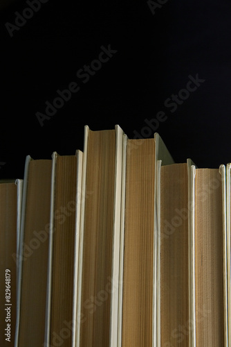 Books on a black background, vertical snapshot, books with white covers on a dark background