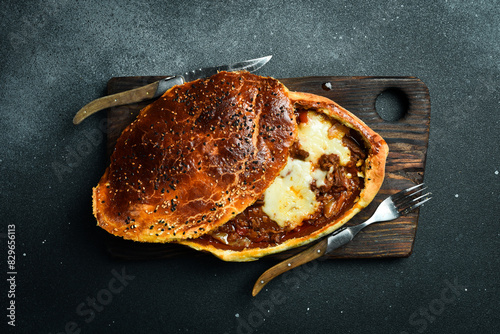 Turkish pide with minced lamb, tomatoes, bell pepper. Traditional dish. On a black stone background. photo