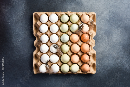 Organic raw chicken eggs in a cardboard box. Food is enriched with proteins. On a stone background. Top view.