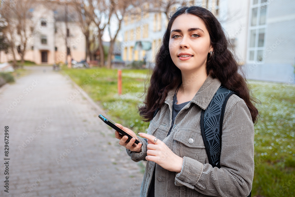 Φωτογραφία Portrait of pretty young Caucasian woman looking at camera and holding phone in her hand