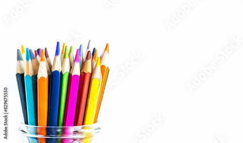 A vibrant collection of colored pencils arranged in a glass jar against a white background with copy space. Concept for back to school and creativity-themed content.