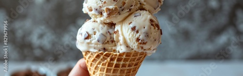A hand firmly grips a cone filled with three scoops of ice cream