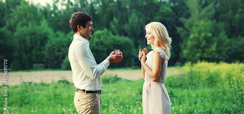 Wedding happy lovely young couple, man proposing a ring to his beloved woman outdoors in summer park photo
