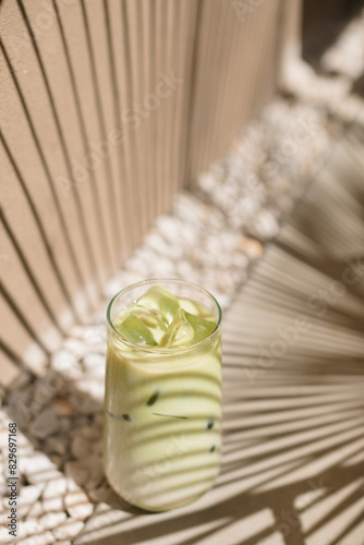 A glass of matcha latte with dappled light in the summer. Vacation, holiday, mocktail, summer bar menu