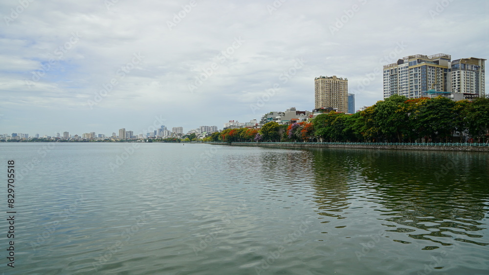 City landscape next to the lake, green trees blooming colorful flowers City landscape next to the lake, green trees blooming colorful flowers