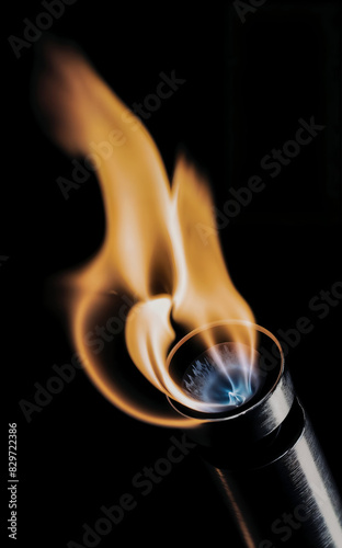 A beautiful rainbow flame bursts from the propane torch on the black background