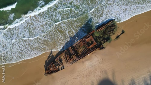 4K Drone Ariel Video spinning around the Maheno Shipwreck by the blue green ocean on the beach on K'Gari Frasier Island, Queensland Australia. photo