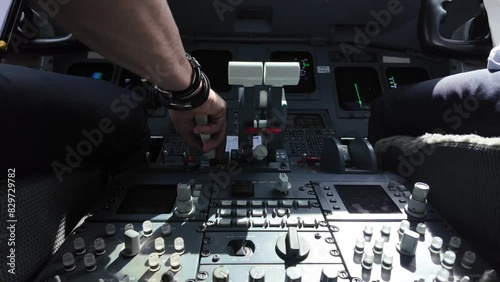 Real time scene inside a jet cockpit while flaying across turbulence area. Captain piloting the plane using speed brakes and thrust levers. Daylight. Camera between both pilots, low angle. 4K 60FPS.